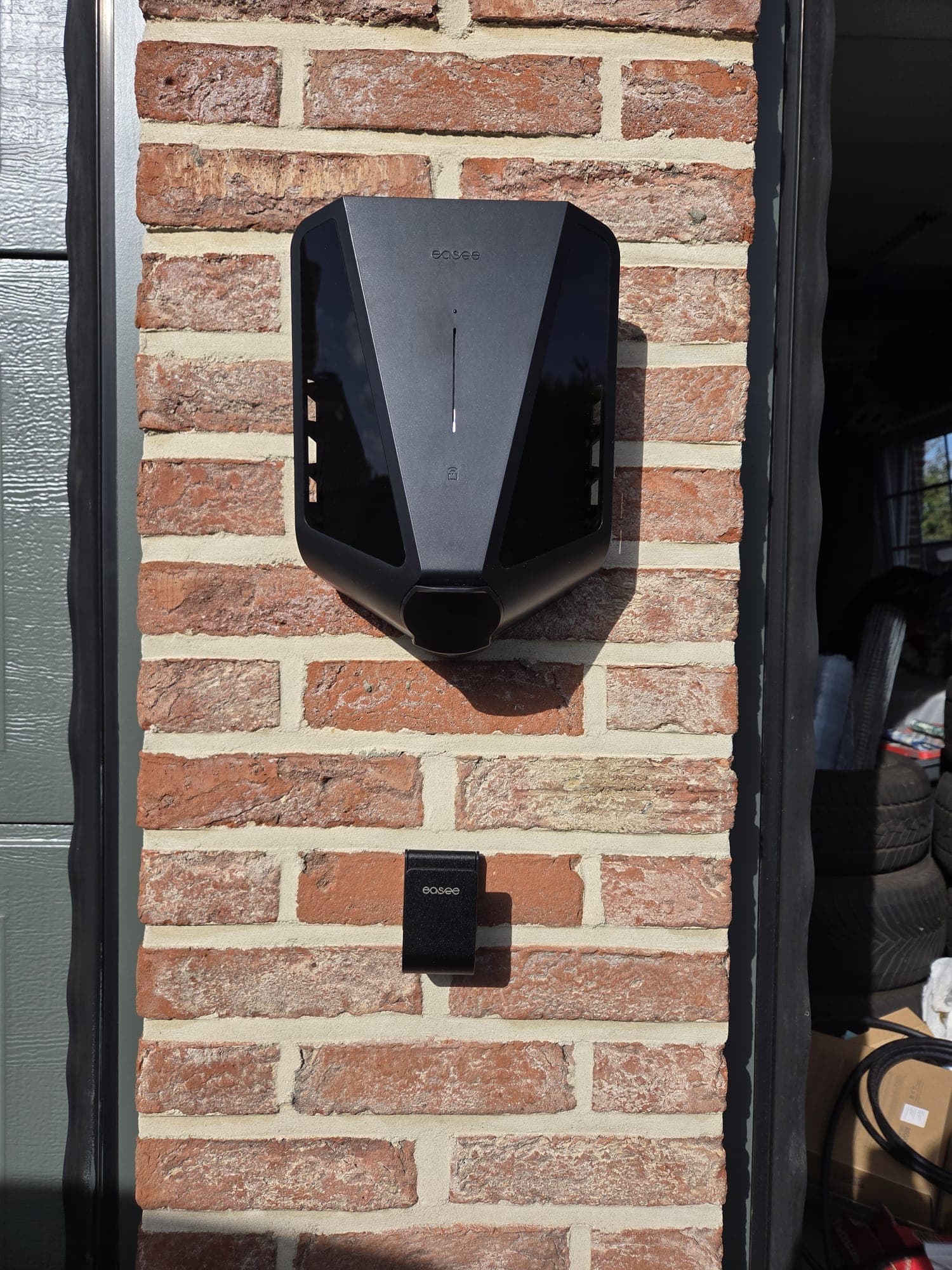 Electric car charging in front of a brick garage