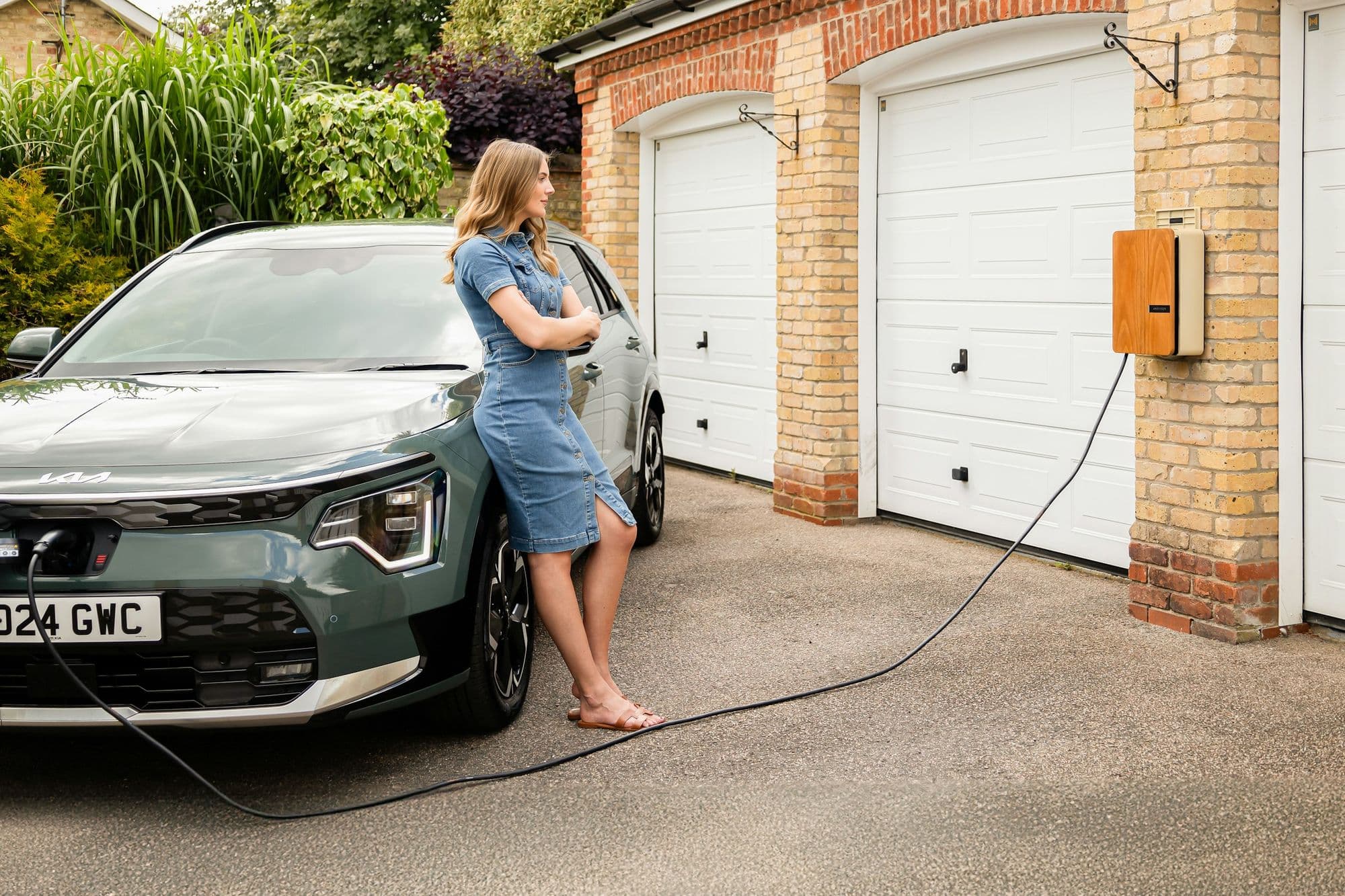 Voiture électrique en charge devant un garage en briques